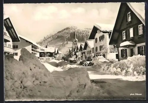 AK Oberstaufen /Allgäu, Winterliche Ortsansicht mit Kirche und verschneiten Strassen