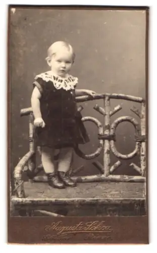 Fotografie Augusta Schou, Rönne, Lille Torv, Kind auf einem Holzstuhl