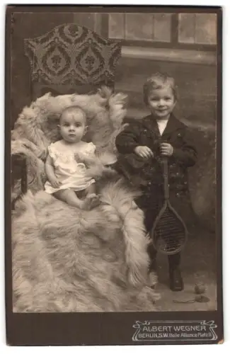 Fotografie Albert Wegner, Berlin, Belle Alliance Platz 9, Junge mit Tennisschläger und Kleinkind auf Fell