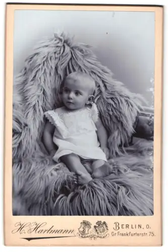 Fotografie H. Hartmann, Berlin, Gr. Frankfurterstr. 75, Porträt eines Kleinkindes auf einem flauschigen Sessel