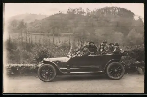 Foto-AK Auto mit Damen- und Herrengesellschaft bei einem Ausflug in hügeliger Landschaft