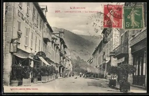 AK Entraygues, La Grand`rue animée avec vue sur les montagnes en arrière-plan