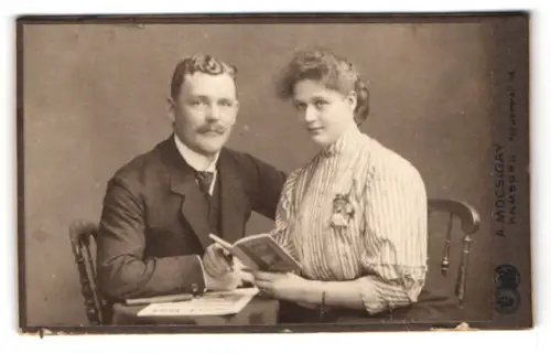 Fotografie A. Mocsigay, Hamburg, Neuerwall 46, Paar mit Buch an einem Tisch sitzend