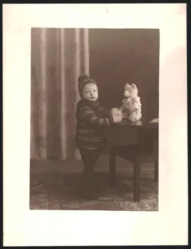 Fotografie junger Knabe mit seinem Teddybär auf dem Tisch