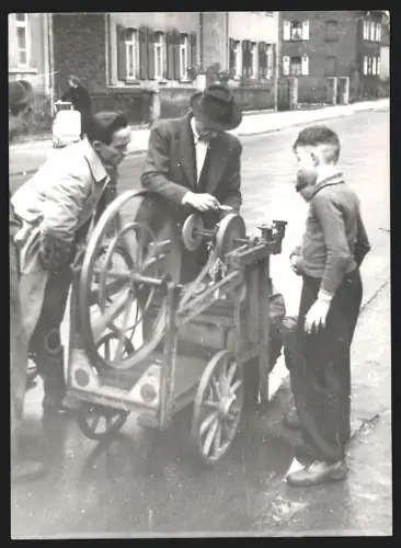 Fotografie junge Knaben bestaunen einen Messerschleifer an seiner Schleifmaschine