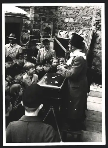 Fotografie Zauberer / Magier belustigt Kinder mit seinen Zaubertricks, Strassenkünstler