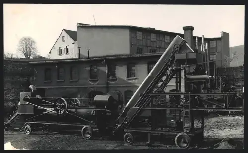 Fotografie Drehrohrofen mit Fördergerät vor einer Werkhalle