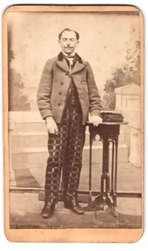 Fotografie Josef Karl, Arnstorf, Mann in gemusterter Hose neben Tisch