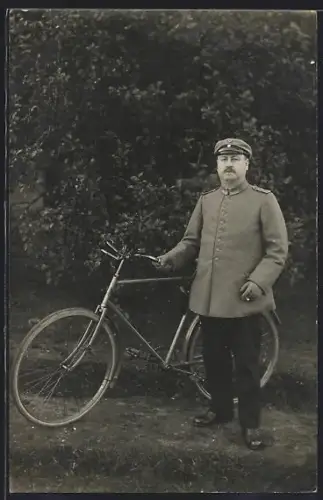 Foto-AK Soldat in Feldgrau Uniform mit Schirmmütze und Fahrrad