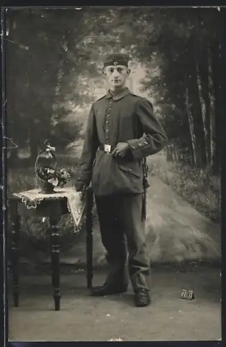 Foto-AK Soldat in Uniform neben einem Tisch mit Blumenkorb