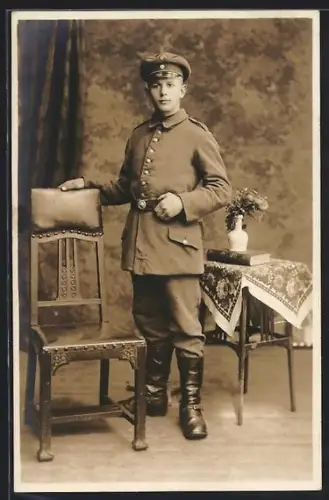 Foto-AK Soldat in Uniform lehnt an einem Stuhl