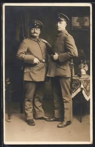 Foto-AK Zwei Soldaten in Uniformen posieren neben einem Tisch