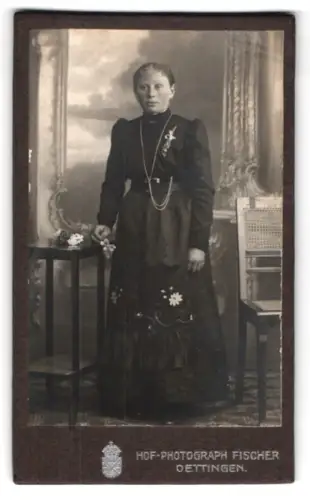 Fotografie Fischer, Oettingen, Frau im dunklen Kleid neben Tisch