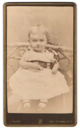 Fotografie J. Scharf, Bad Freienwalde, Porträteines Kleinkinds auf einer Bank
