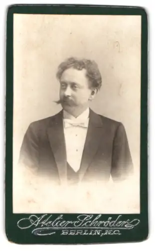 Fotografie Atelier Schröder, Berlin, Herr im Anzug mit Fliege