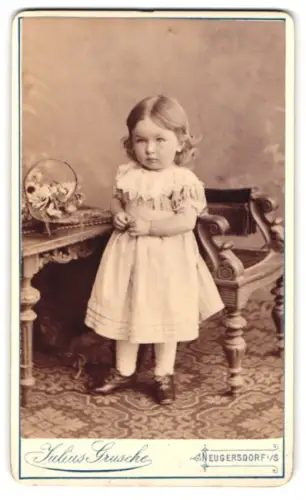 Fotografie Julius Grusche, Neugersdorf, Kind im Kleid neben Stuhl