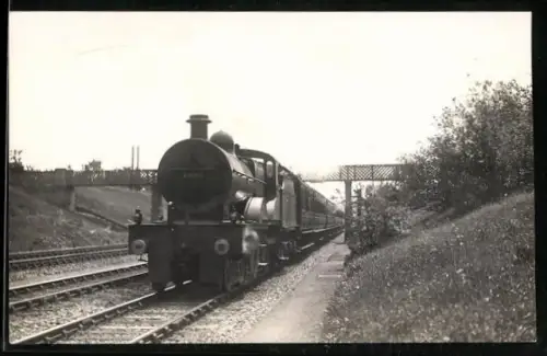 AK Britische Lokomotive Nr. 1022 mit Personenwaggons nach Unterfahren einer Brücke, englische Eisenbahn