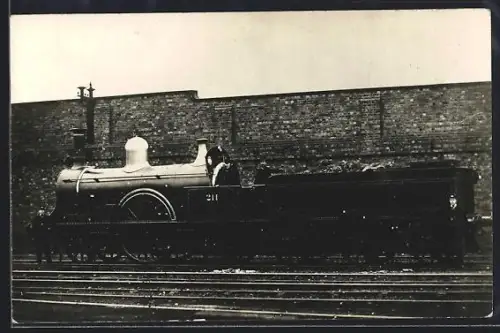 AK Britische Lokomotive Nr. 211 mit Tender vor einer Ziegelmauer, englische Eisenbahn