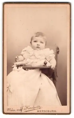Fotografie F. Herrfurth, Merseburg, Brühl 4, Porträt eines Kleinkindes auf einem Stuhl im März 1889