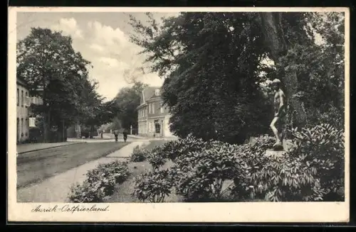 AK Aurich / Ostfriesland, Blick auf Grünanlage mit Statue und Strassenpartie