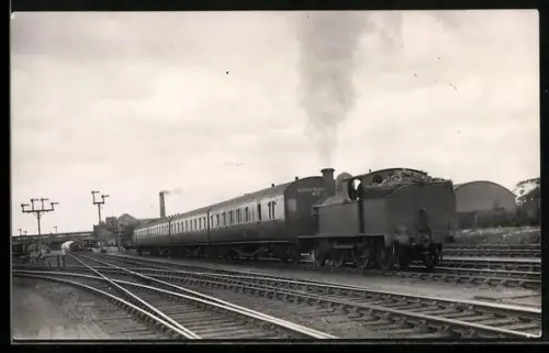 Foto-AK Britische Lokomotive schiebt vier Personenwaggons in einen Bahnhof, englische Eisenbahn