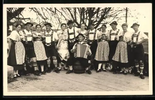 AK Tanzgruppe in ihren bayrischen Trachten, Akkordeon-Spieler sitzt auf dem Fass