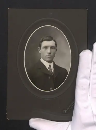 Fotografie Burkholder Studio, Mansfield / OH., junger Amerikaner im dunklen Anzug mit stählendem Blick