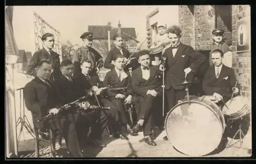 Foto-AK Gruppenfoto von Musikern mit diversen Instrumenten, angeordnet um eine Trommel