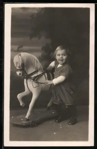 AK Kind neben einem Schaukelpferd