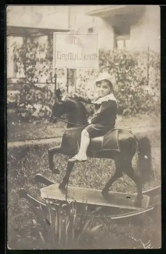 Foto-AK Kind sitzt auf einem Schaukelpferd im Garten