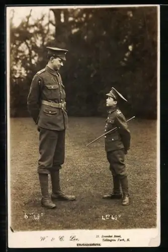 AK Mann in Uniform steht vor einem sehr jungen Kind, das ebenfalls Uniform trägt