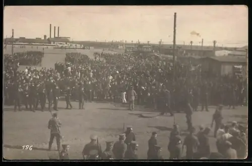 Foto-AK Soltau, Kriegsgefangenenlager, Grupenaufnahme von Gefangenen, im Hintergrund das Kraftwerk