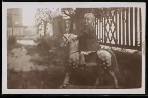 Foto-AK Kleines Kind sitzt stolz auf einem Pferdespielzeug