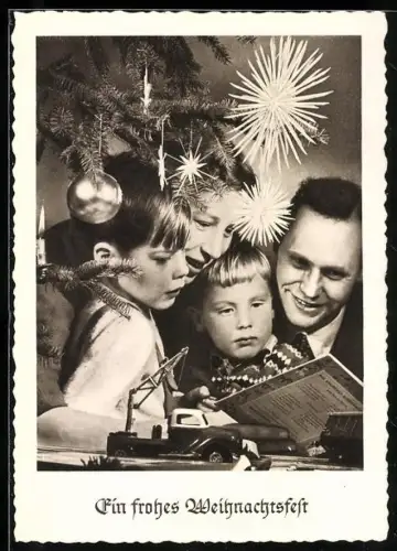 AK Familie unter einem Weihnachtsbaum mit einem Spielzeugkran aus Blech