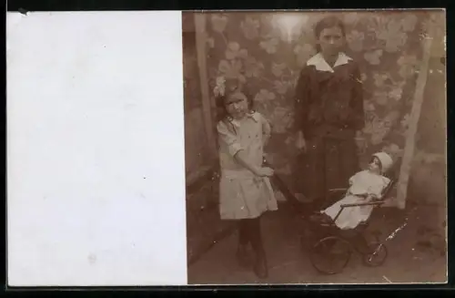Foto-AK Kinder mit einem Kinderwagen, in dem eine Puppe sitzt