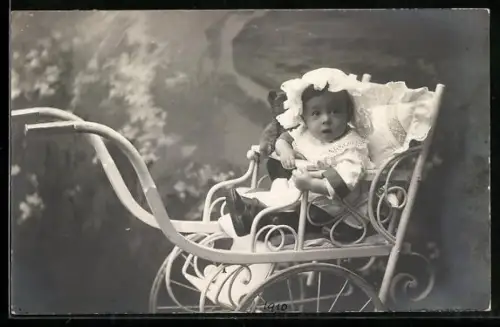 Foto-AK Kleinkind mit Haube in einem Kinderwagen