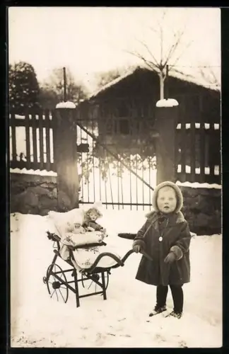 Foto-AK Kleines Kind im Schnee mit einem Kinderwagen, in dem eine Puppe sitzt
