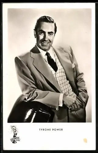 AK Schauspieler Tyrone Power, stehend auf einen Sessel gelehnt