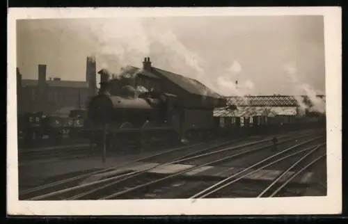 AK Britische Lokomotive mit Tender und Güterwaggons in einem Bahndepot, englische Eisenbahn
