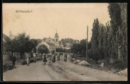 AK Wilfersdorf /N.-Oe., Strasse mit Kirche und Passanten