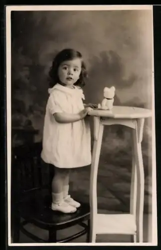 AK Kleines Kind steht bei einem Tisch mit einem kleinen Teddy