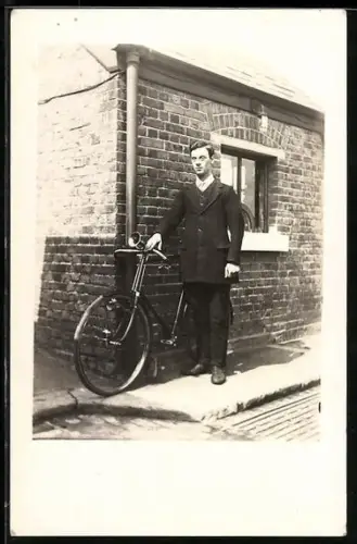 Foto-AK Junger Mann mit seinem Fahrrad vor einem Backsteingebäude