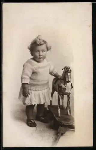 Foto-AK Kleinkind neben einem Schaukelpferd