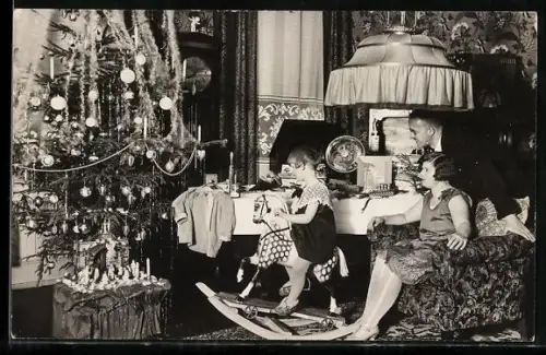 Foto-AK Kind auf einem Schaukelpferd mit seiner Familie am Weihnachtsbaum