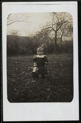 Foto-AK Kleines Kind mit Puppe auf einer Wiese