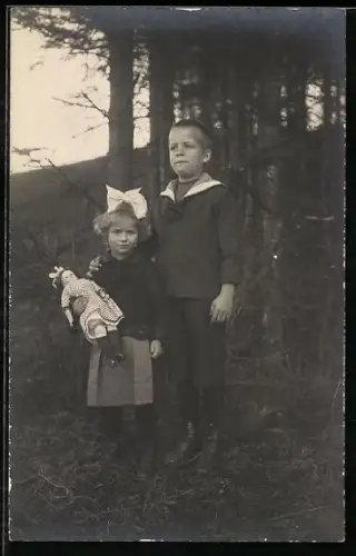 Foto-AK Kinderpaar mit Puppe auf einer Wiese