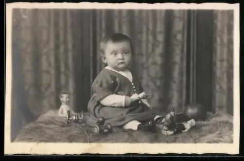 Foto-AK Kleines Kind mit Puppen sitzt auf Fell