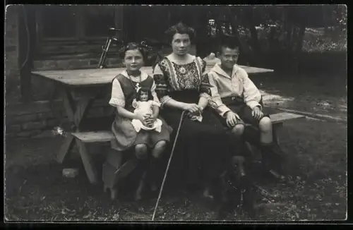 Foto-AK Frau und Kinderpaar mit Puppe im Garten