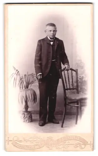Fotografie Paul Müller, Rønne, Lille Torv, Junge im Anzug neben Stuhl