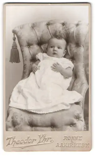 Fotografie Theodor Yhr, Rønne, Kleinkind auf elegantem Sessel